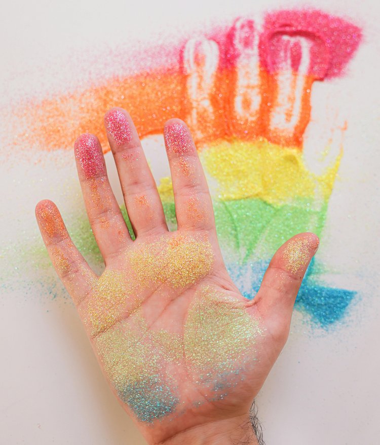 Handabdruck in Regenbogenfarbenem Sand