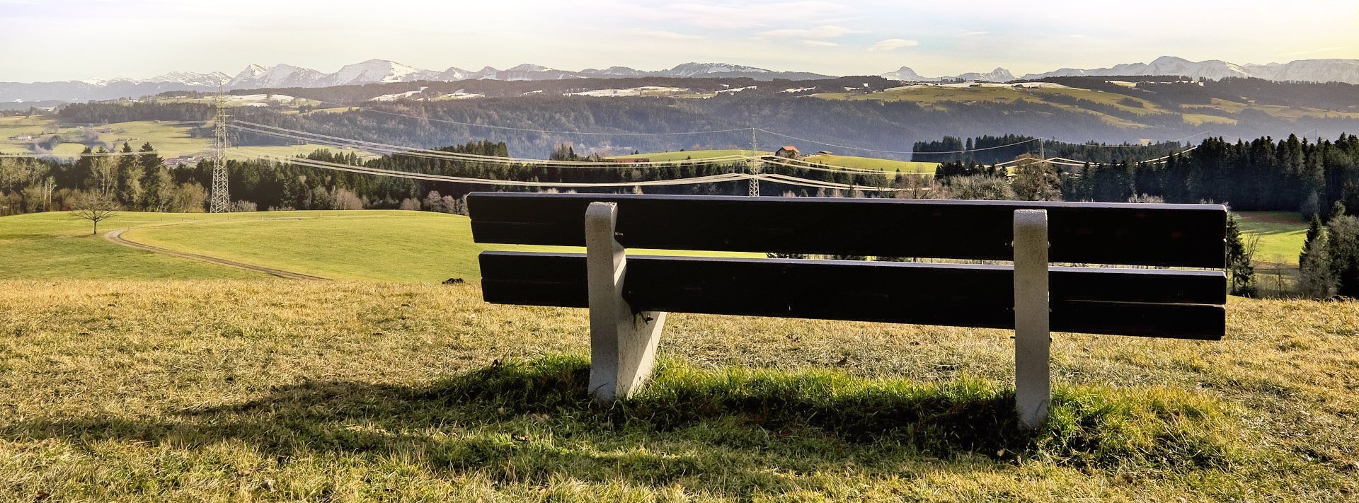 einsame Bank auf Wiese, Berge im Hintergrund