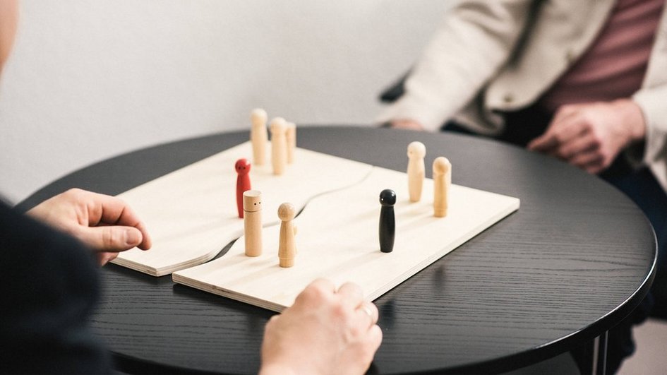 Zwei Menschen an einem Tisch mit Holzfiguren