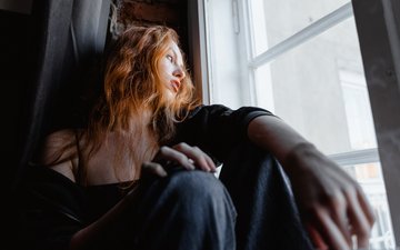 Frau schaut nachdenklich aus dem Fenster