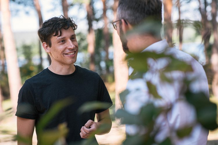 Psychotherapie-Sitzung: Therapeut und Patient im Gespräch, im Hintergrund Bäume