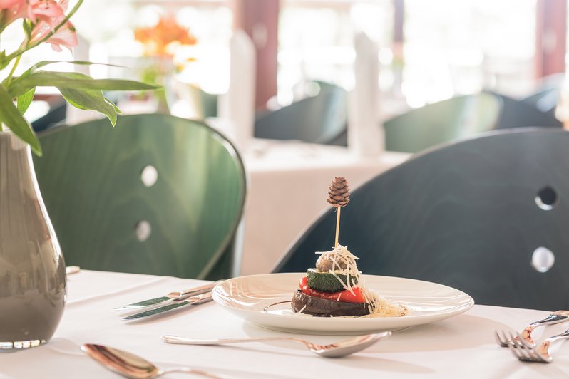 Nahaufnahme eines liebevoll dekorierten Gerichts. Teller steht auf gedecktem Tisch. 